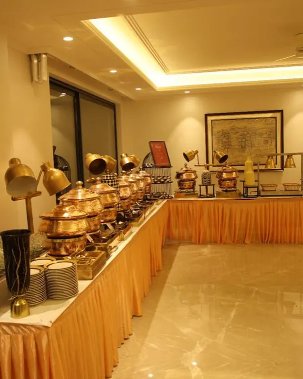 A full view of my buffet setup for a Grah Pravesh (housewarming) party. The arrangement features a long line of gleaming copper chafing dishes, neatly stacked plates, and elegant decor, creating a grand and welcoming feast.