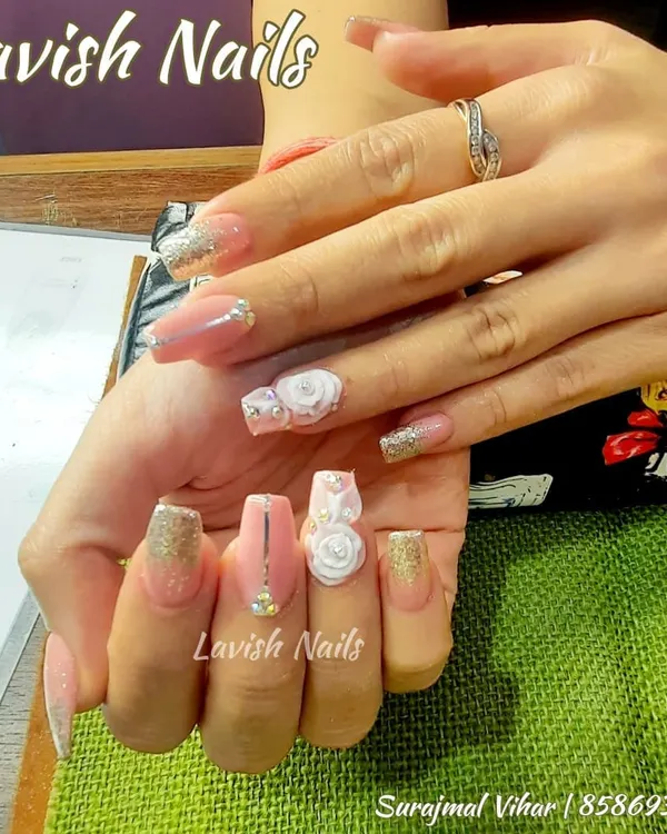 An exquisite bridal nail set featuring 3D white roses, gold glitter, and delicate rhinestone details on long pink acrylics.