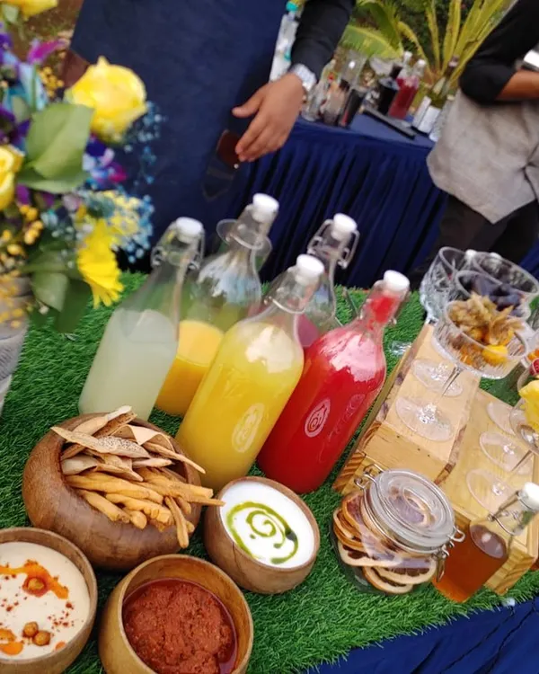 A vibrant spread of fresh ingredients for my Garden Fresh cocktail bar. This setup includes bowls of dips, breadsticks, and bottles of colorful, freshly squeezed juices and syrups ready for mixing.