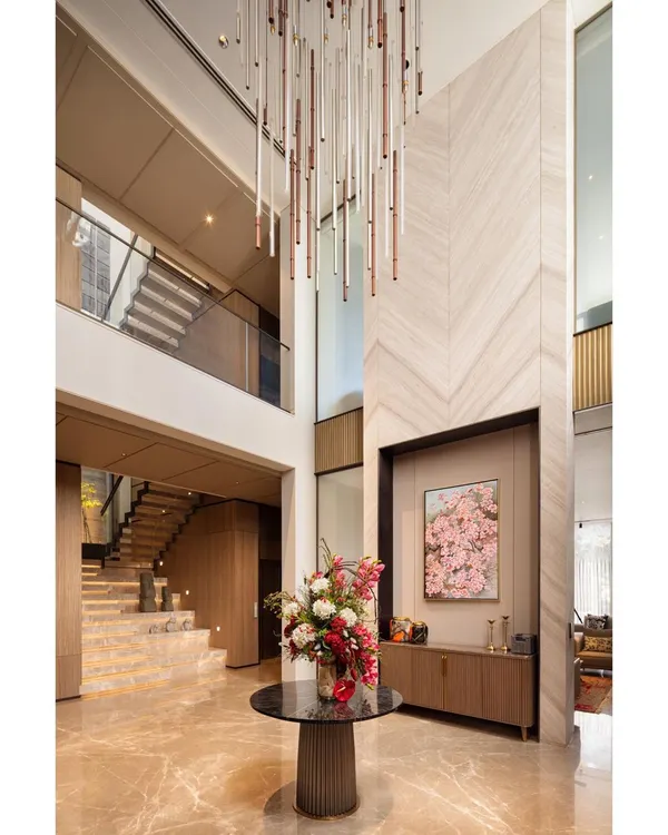 The foyer of the Punjabi Bagh villa showcases our orchestration of volumes. A custom chandelier cascades through the double-height space, drawing the eye upwards and highlighting the chevron-patterned marble and grand staircase.