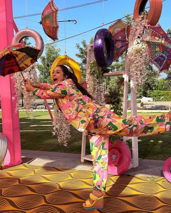 How do I stay so fit? By doing yoga in heels right in the middle of a show. A fun, quirky shot from a colorful Mehendi event, showing off my playful side and a very unique outfit.