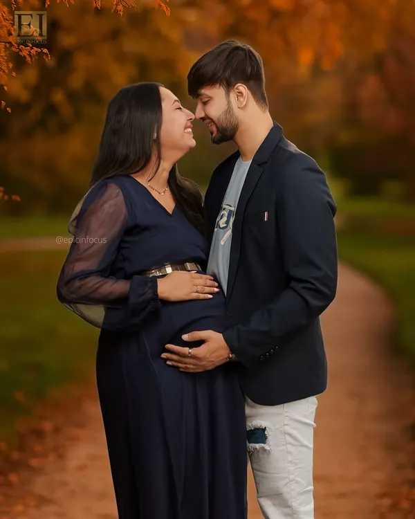 An intimate moment between partners in a beautiful autumn park setting. This couple's maternity photo highlights the warmth and connection as they await their baby.