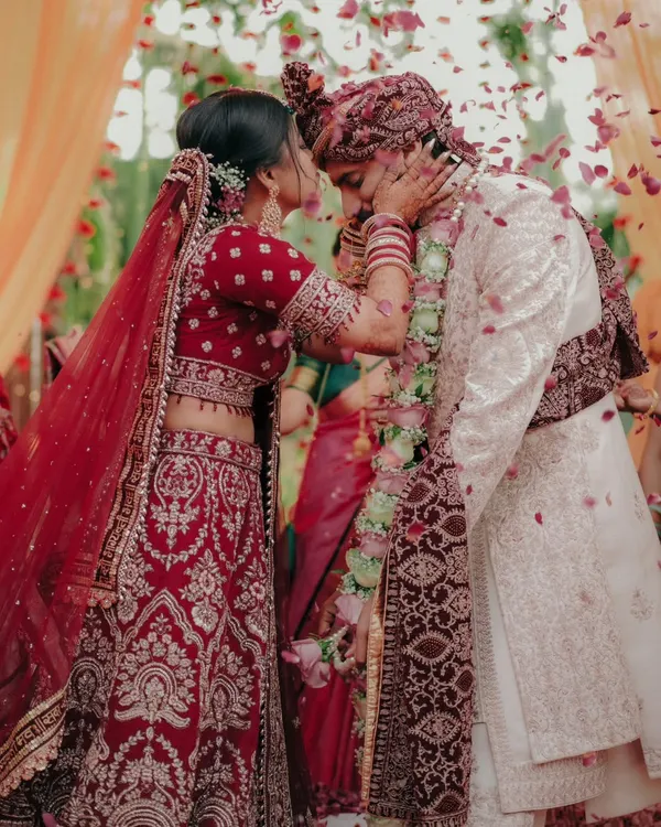 A moment of gentle affection during the wedding ceremony. The bride lovingly touches the groom's face, surrounded by a shower of petals, a candid expression of their bond.
