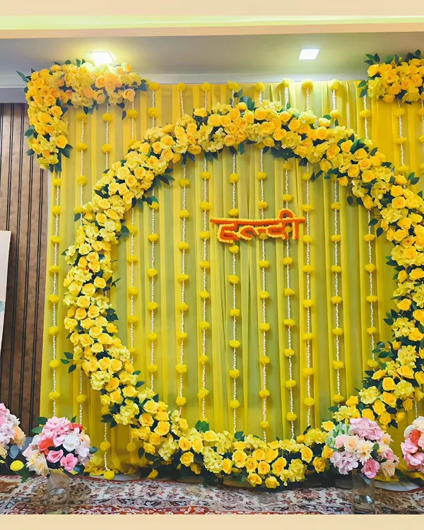 A beautiful and traditional Haldi ceremony backdrop. The vibrant yellow of the marigold floral ring and drapes brings so much light and happiness to this special pre-wedding event.