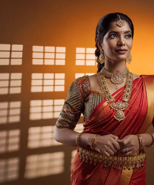 A stunning studio portrait of a bride in a red silk saree. The creative lighting with a window-pane shadow effect adds a touch of artistic flair to this classic bridal shot.