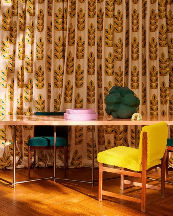 A vibrant dining space where floor-to-ceiling curtains feature a bold, embroidered leaf motif from Élitis. The pop-inspired colors and graphic pattern demonstrate how custom drapery can become a central artistic feature in a room, setting a joyful and energetic tone.