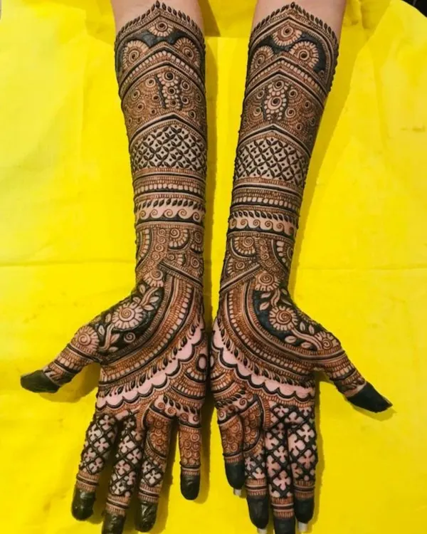 A full-coverage engagement mehendi with symmetrical patterns. The design features a mix of geometric grids, paisleys, and floral elements for a rich and detailed look.