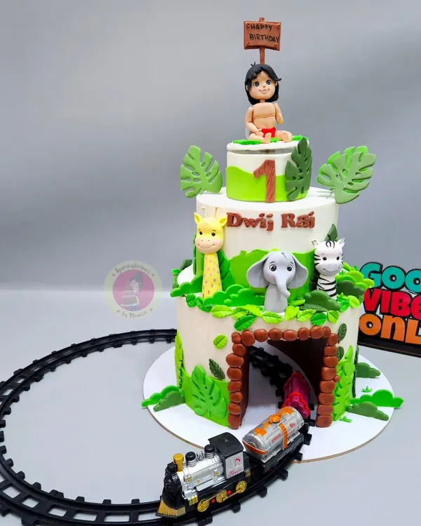 A three-tiered Jungle Book cake for a first birthday, complete with a toy train running through a tunnel in the bottom tier. This cake combines fondant art with interactive elements to create a truly magical experience.