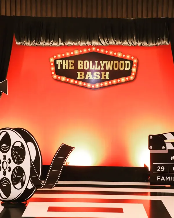 The main backdrop for 'The Bollywood Bash,' a get-together event for Fern Hotels & Resorts. The design features a classic cinema marquee sign against a vibrant red curtain, setting the perfect tone for a film-themed party.