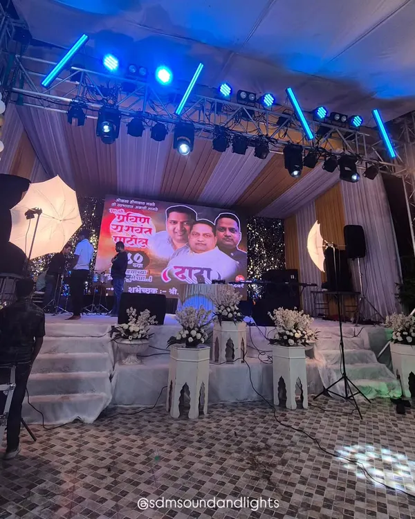 A stage setup for a large birthday celebration, featuring a prominent central LED screen. The professional lighting truss above is equipped with programmable lights to create dynamic effects that match the event's energy.