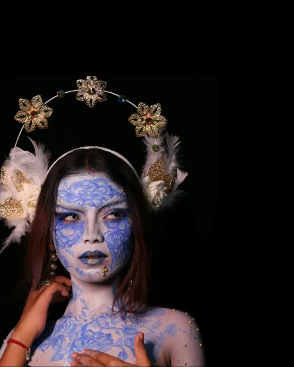 A portrait that transcends reality. This is a high-concept fantasy shoot, where we used intricate blue and white body paint and a custom floral headdress to create a living piece of art.