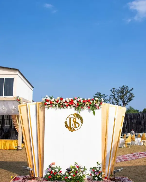 A custom monogram displayed as a grand centerpiece for an outdoor wedding event. The golden 'RS' logo stands out beautifully against the white and gold backdrop, creating an elegant and impactful focal point for the celebration.