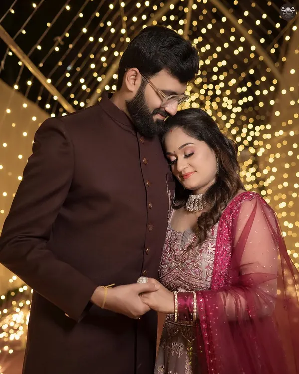 A romantic portrait of a couple at their evening reception. The warm bokeh from the string lights creates a beautiful, dreamy effect, perfect for engagement or reception photography.