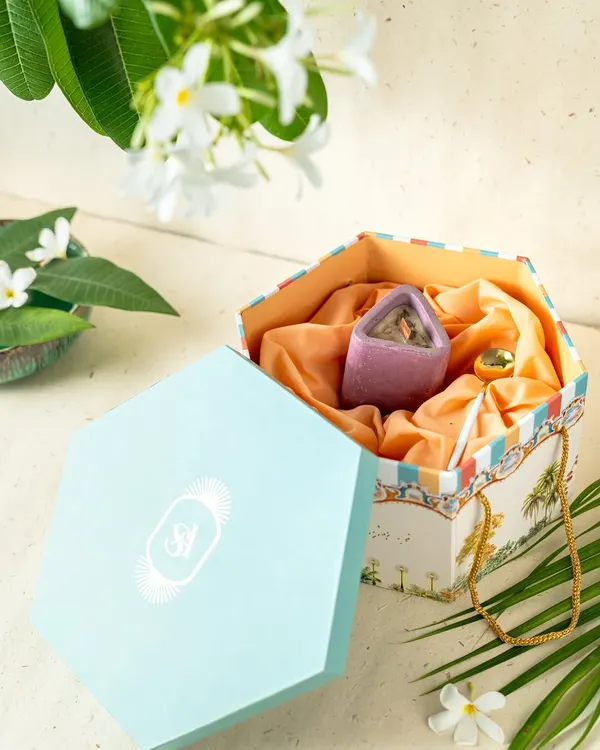 A custom hexagonal gift box designed as part of a wedding invitation suite. The exterior features artwork inspired by the couple's story, and the interior is lined with silk, holding curated gifts for the guests.