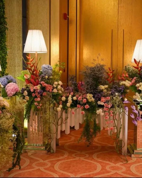 A beautiful pastel-themed setup for a daytime event. The console table is overflowing with a lush arrangement of hydrangeas, roses, and other florals in soft pinks, blues, and purples.
