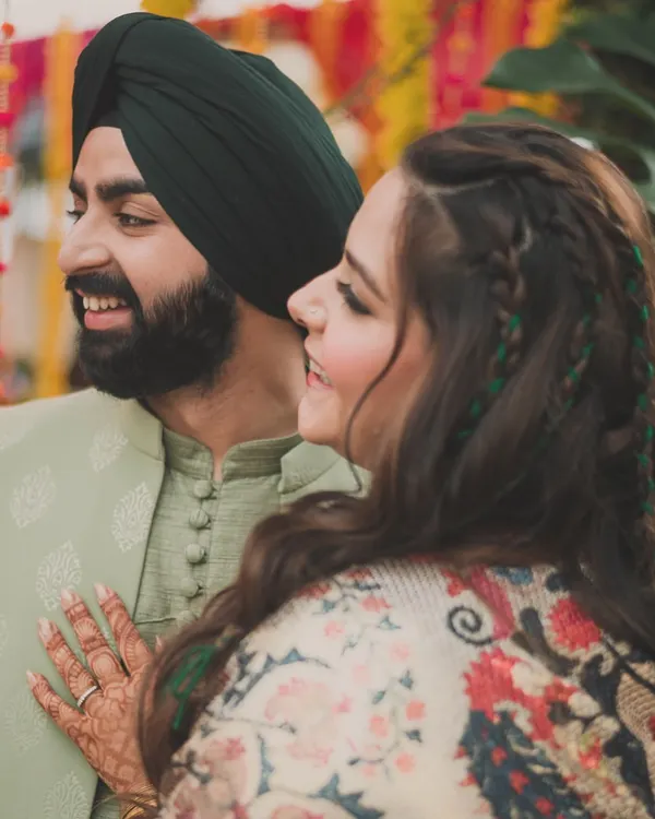A happy moment between the bride and groom during their mehendi. We chose a handsome pistachio green outfit for him, which contrasted beautifully with her printed kaftan, creating a stylish and coordinated couple look.