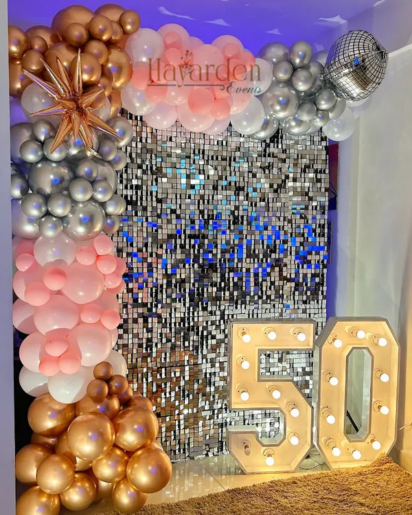 A fabulous 50th birthday celebration. The large light-up '50' is the star of the show, complemented by a silver sequin wall and a rose gold and pink balloon garland.