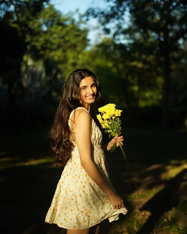 A candid moment of joy in the park. The natural sunlight filtering through the trees creates a beautiful, soft light that feels warm and genuine.