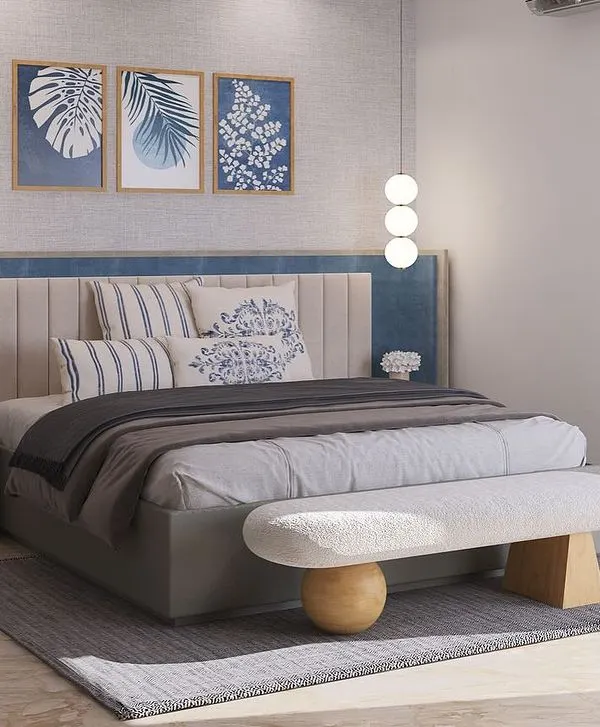 This bedroom design for a DLF Phase 2 project invites calm with a layered palette. The custom bed features a wide, two-tone upholstered headboard, complemented by a sculptural bench and hanging globe lights.