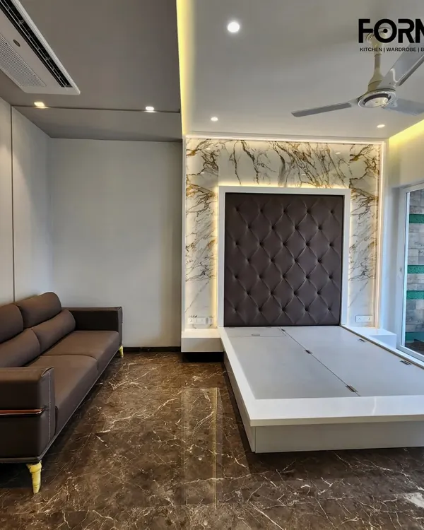 Here, a classic diamond-tufted headboard in dark fabric is framed by a stunning marble-effect feature wall with warm backlighting. The sleek, low-profile bed frame is designed with a lift-up mechanism for convenient under-bed storage.