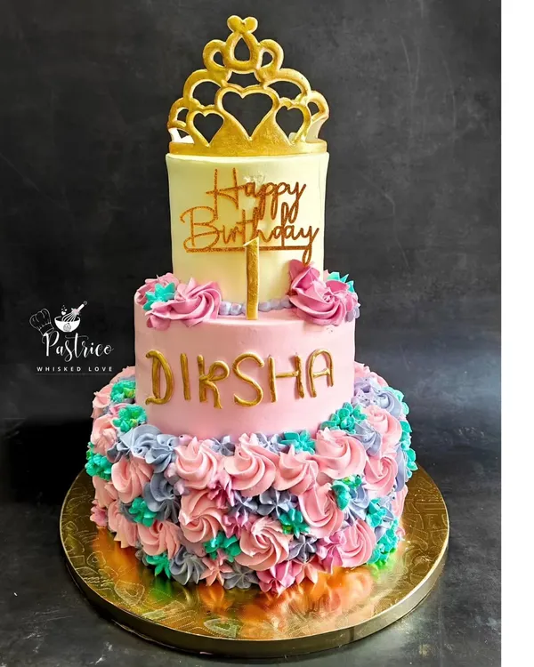 A beautiful two-tiered princess cake for a first birthday, with a cascade of colourful frosting rosettes and an edible gold crown.