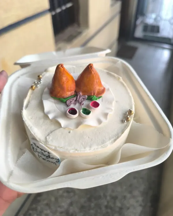 This custom samosa-themed bento cake is a perfect example of how we can turn any inside joke or craving into a sweet celebration. It features two fondant samosas complete with edible chutney, all packed in a convenient takeaway box.