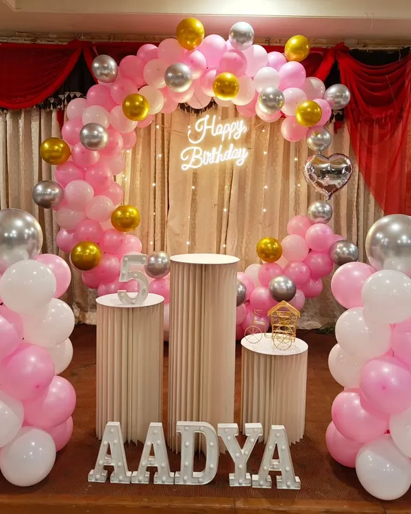 A beautiful pink, white, and silver balloon arch with a neon 'Happy Birthday' sign. This classic setup is perfect for a sweet and stylish celebration.