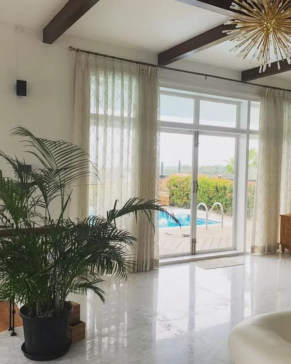 The main living area of this Mysore residence is defined by its direct connection to the rooftop pool. The open-plan layout, high ceilings with wooden beams, and large glass doors make the space feel expansive and full of light.