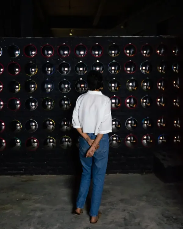 A viewer interacting with the 'Surfing' installation. The wall of mirrors creates an engaging and thought-provoking experience, making the observer a part of the artwork itself.