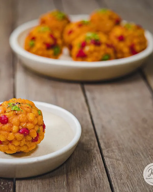 A perfect, single Jodhpuri Laddoo, also known as Boondi Laddoo. It's studded with colourful boondi and nuts, making it as beautiful as it is delicious.