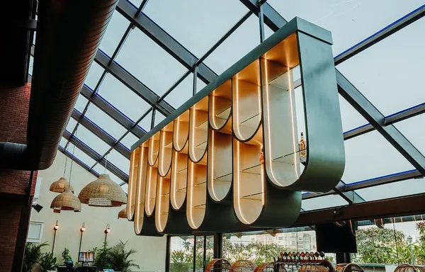The centerpiece of this resto-bar is the sculptural, suspended bar display, which adds drama and artistry to the space, especially under the glass ceiling.