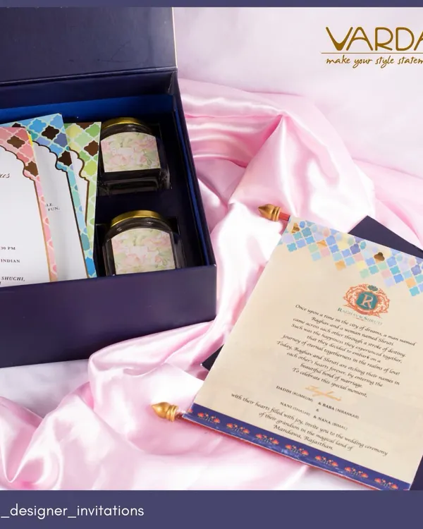 A custom wedding invitation suite in a deep blue box. This design features cards with a modern mosaic pattern, paired with jars of gourmet treats for a complete gifting experience.