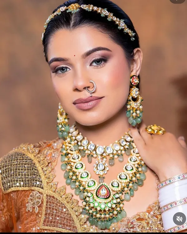 A close-up of this stunning bridal look. The layered Kundan necklace with green beadwork, matching matha patti, and nath creates a breathtakingly beautiful effect.