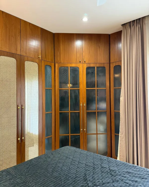 Custom wardrobes so sleek, even your clutter feels expensive. Cane meets glass and rich wood in this cozy corner glow-up.
