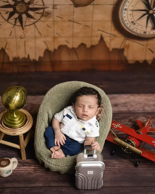 Ready for takeoff! This little pilot is all set for his first adventure, surrounded by a vintage map, a toy plane, and a globe. It’s a perfect theme for travel-loving families.