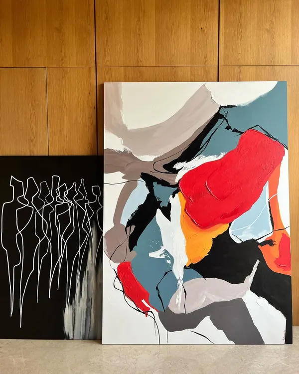 A pair of commissioned abstract canvases. One is a 'Colour Cluster' with bold, expressive shapes, while the other is a minimalist monochrome piece titled 'Bad shapes drawn carefully', exploring form through simple lines.