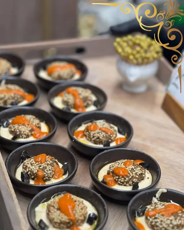 Falafel, but with a gourmet twist. I serve my sesame crusted falafel in individual bowls on a bed of creamy hummus, topped with a flavorful red pepper sauce.