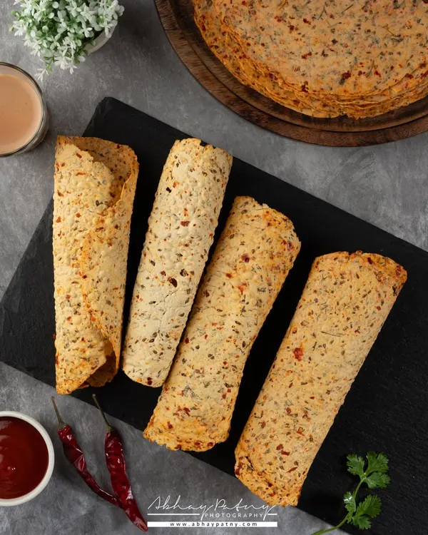 This flat lay of khakhra or papad is styled with chai and chutney, presenting it as a perfect tea-time snack. The composition is clean and balanced.