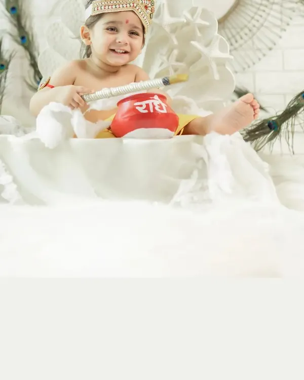 A close-up of a smiling baby dressed as little Krishna for a Janmashtami photoshoot. The details of the costume, the pot of butter, and the joyful expression make this a perfect festive portrait.