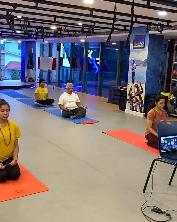 A hybrid yoga session in action, with some participants joining in person and others connecting remotely via a live video stream. This flexible model ensures that no team member misses out, regardless of their location.