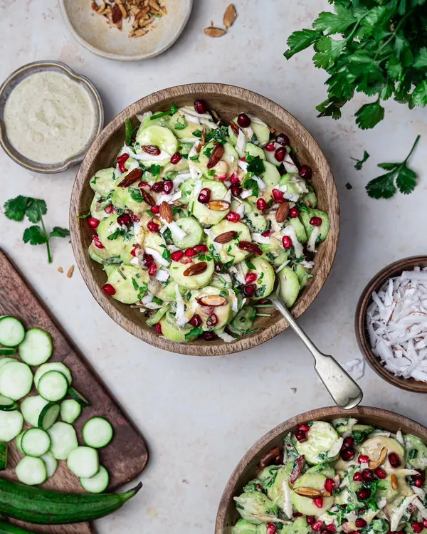A refreshing cucumber salad with pomegranate and almonds. This top-down shot uses natural light and wooden bowls to create a fresh, earthy, and wholesome feel.