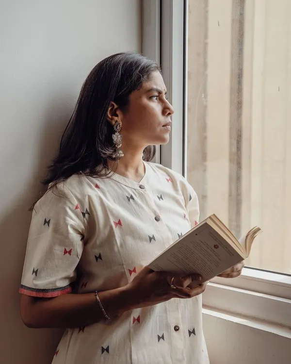 A thoughtful portrait by the window, using soft, natural light to create a serene mood. This shot is part of a lifestyle campaign for an Indian wear brand, perfect for their website or social media.