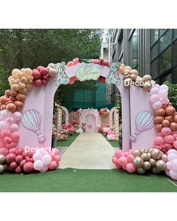 A grand entrance for a pink teddy bear themed party. The large arch is decorated with pink and rose gold balloons, welcoming guests to a beautiful outdoor celebration.