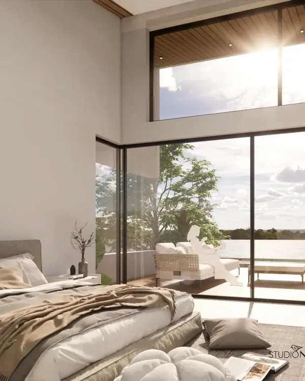 This master bedroom in our Mangalore waterfront project was designed to feel like a private retreat. Floor-to-ceiling glass walls dissolve the boundary between the interior and the expansive river view, while the high, angled ceiling enhances the sense of space and light.