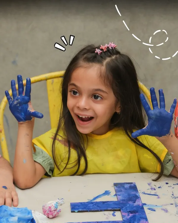 The pure excitement of a creative breakthrough. This young guest at a birthday party is thrilled with her paint-covered hands, fully immersed in the fun of making art.