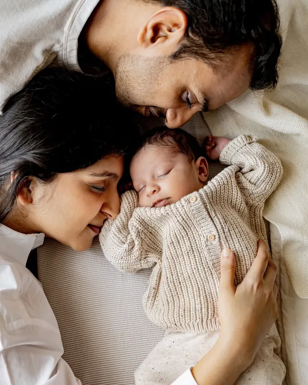 A quiet moment with mum and dad. This overhead shot of a newborn sleeping peacefully in their parents' arms shows the beautiful, protective bubble of love that surrounds a new baby. I love capturing these serene moments during in-home newborn sessions.