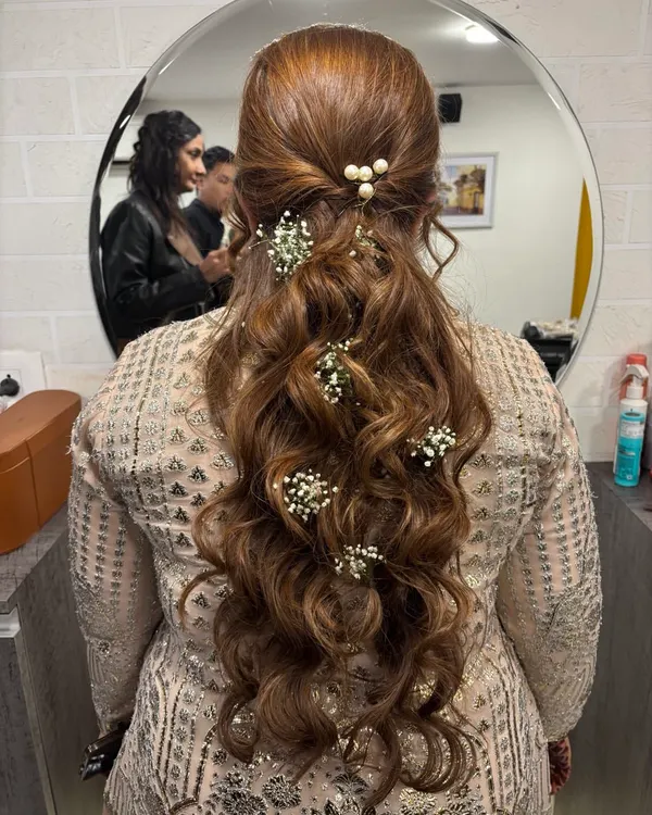 A beautiful example of a half-up, half-down hairstyle with soft waves. I adorned it with delicate baby's breath and pearls for a touch of elegance, perfect for a reception or sangeet.