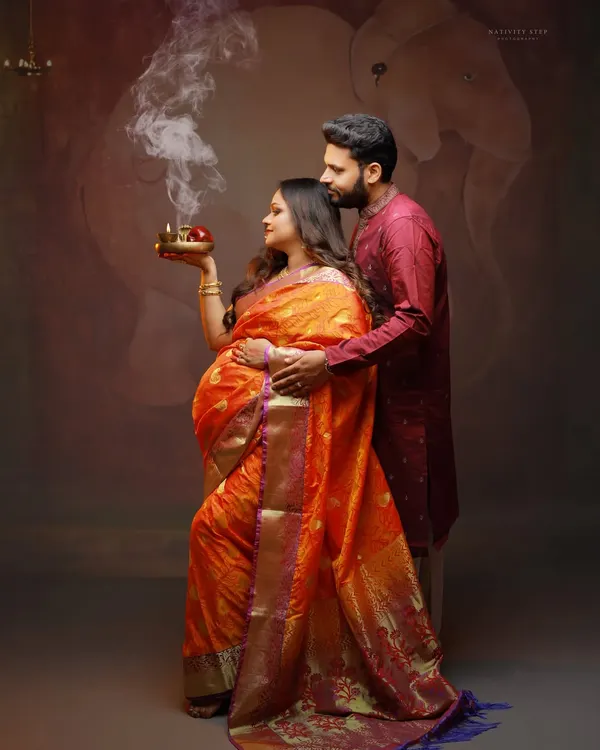 An intimate moment between expecting parents, celebrating their journey with traditional elements like the ceremonial diya. This studio shot combines cultural reverence with artistic lighting.