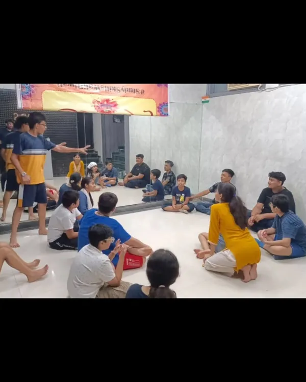 A theatre workshop in session, with students sitting in a circle for a script-reading and character development exercise. This collaborative approach is central to how we create our original plays.