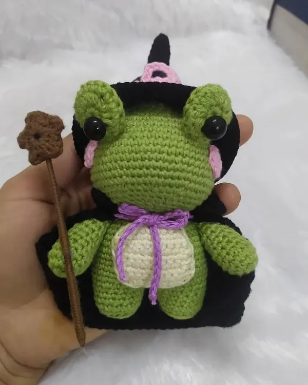 Holding the little wizard frog to show his size. He's a perfect handful of magic, with his little cape and wand all securely stitched on.